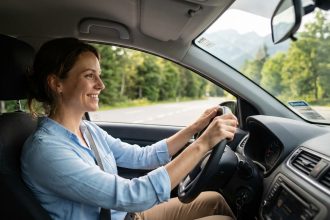 Femme souriante dans une voiture en extérieur avec paysage montagneux