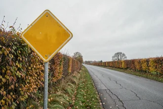 Panneau losange jaune sur poteau métallique au bord d'une route rurale française en automne